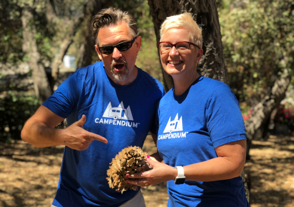 Happy people wearing Campendium t-shirts and holding a gigantic pinecone